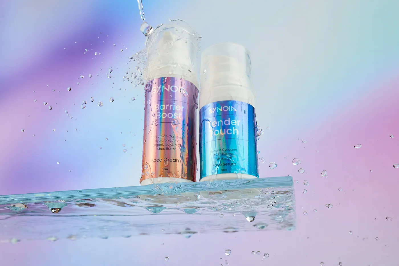 SYNOIA Barrier Boost cream and Tender Touch serum on a glass shelf, in a splash of water