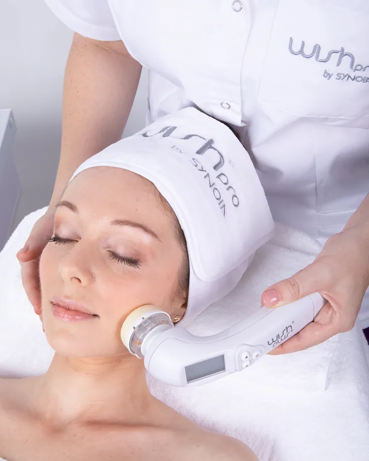 A cosmetician guiding the WISHpro handpiece across a client’s skin