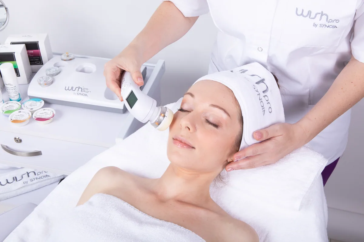 A cosmetician working with the WISHpro handpiece during a session